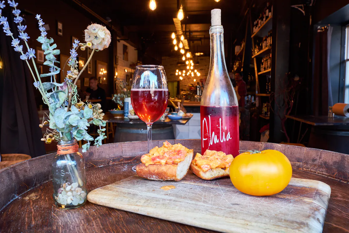 a glass of wine sitting on top of a cutting board with a cake